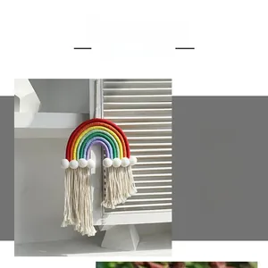 Detailed view of handmade woven cotton rainbow wall hanging with white plush pom-poms and tassels