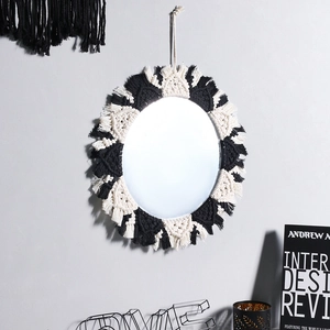 Detail of bohemian macrame mirror with black and white woven fringes on wall
