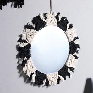 Detailed close-up of bohemian wall mirror featuring black and white woven fringe detail