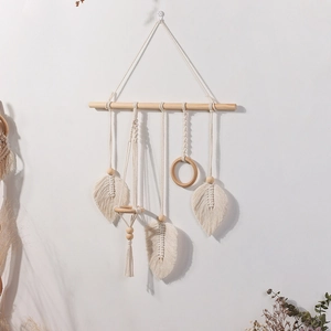Detail of bohemian handmade woven wall hanging with cotton feathers and wood beads
