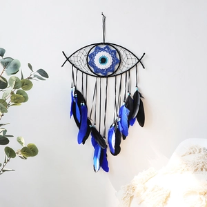 Detail of the evil eye dream catcher featuring blue feathers and wall hanging decor