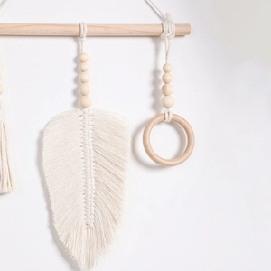 Close-up of handmade macrame wall hanging with woven cotton feathers and wooden beads