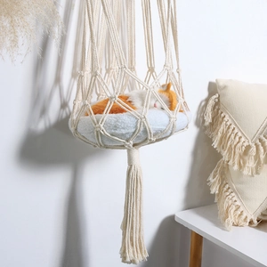 Handmade macrame cat hammock with plush cushion and bohemian tassels in home setting