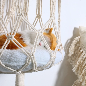 Detail of bohemian hand-woven macrame cat bed with plush cushion and orange plush toy