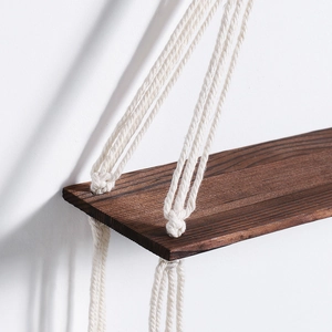 Detail of bohemian wood shelf with deep grain and woven natural cotton rope hanging ties