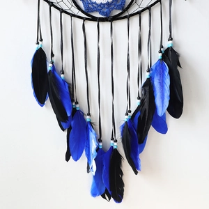 Close-up of vibrant blue and black feathers with decorative beads on evil eye dreamcatcher