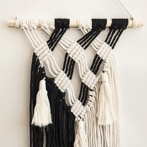 Minimalist handwoven macrame wall hanging in black and white with wooden stick and fringe