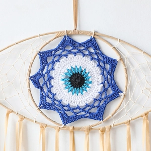 Close-up of handmade Evil Eye dream catcher with intricate blue woven center and white netting