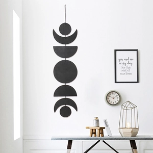 Vertical wall decor featuring seven black phases of the moon hanging on a white wall