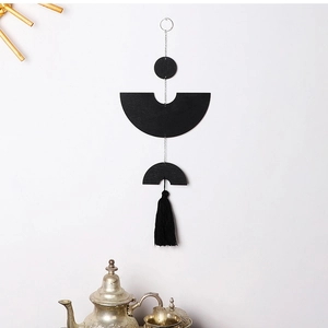Detail of minimalist black geometric wall hanging with wood disks and silk tassels