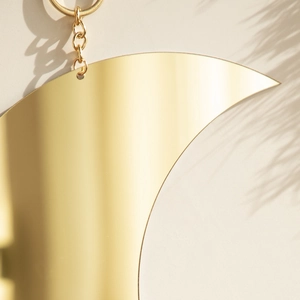 Detailed macro view of a golden moon-shaped wall mirror with elegant metallic hanging chain