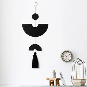 Detail of black geometric wall hanging with wooden discs and tassels in modern room