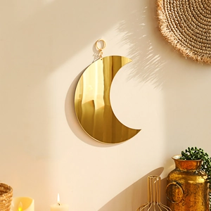 Detailed close-up of bohemian gold crescent moon mirror with hanging chain for wall decor