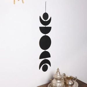 Detail of minimalist black moon phase wall hanging showing crescent to full moon shapes