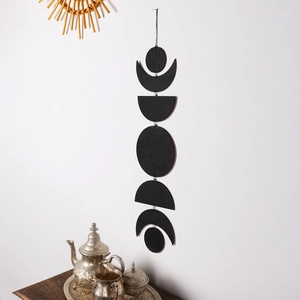 Minimalist moon phase wall decor with five black wooden discs in a vertical line