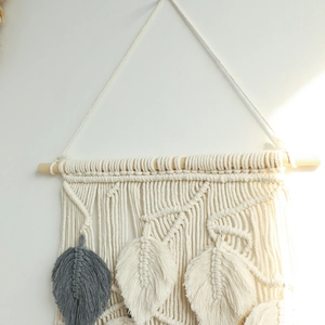 Detail of bohemian hand-woven macrame wall hanging with leaf fringe and wood rod