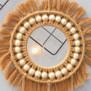 Detail of handcrafted bohemian wall mirror with ginger cotton tassels and wooden beads