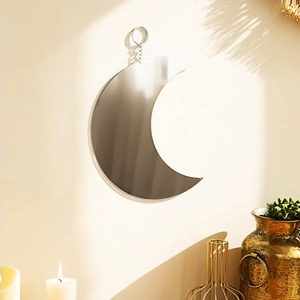 Detail view of crescent moon wall mirror with silver chain hanging on a white textured wall