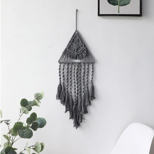 Dettaglio di arazzo bohémien grigio con triangolo geometrico e lunghe nappe decorative