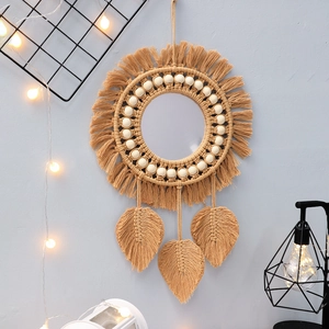 Detail of boho wall mirror with cotton tassels, wooden beads and macrame leaf pendants