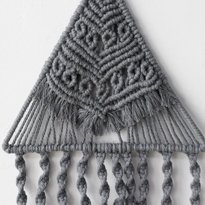 Dettaglio della decorazione murale in macramé grigio fatto a mano con nodi bohémien