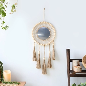 Detail of bohemian woven wall mirror with natural wood beads and macrame tassels