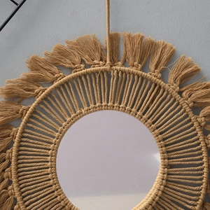 Detail of bohemian round mirror with handcrafted woven cotton rope and beige fringe