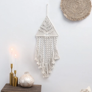 Dettaglio decorazione murale in macramè fatta a mano con telaio a triangolo e nappe di cotone