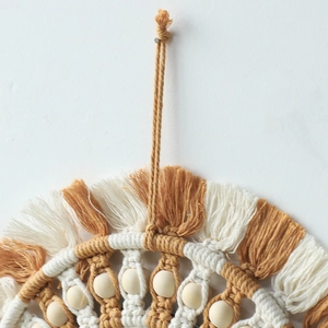 Detail of bohemian macrame wall hanging featuring yellow cotton rope and wooden beads