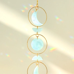 Detail of moon phase suncatcher with gold metal rings and iridescent acrylic lunar phases