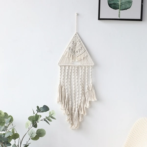 Dettaglio dell'arazzo macramé boho con trama triangolare e morbide nappe di cotone