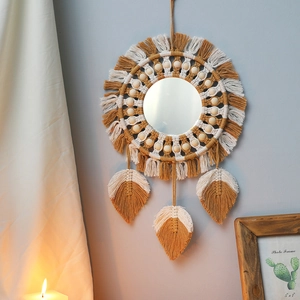 Detail of bohemian handmade woven wall mirror with cotton tassels and wooden beads decor