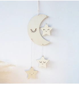 Detailed view of hanging wooden moon and stars wall decor with engraved smiling faces