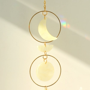 Detailed close-up of moon phase wall hanging with pearlescent finish and golden chain