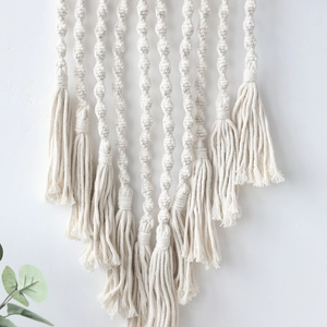 Dettaglio di un arazzo macramè fatto a mano in stile boho con nodi a spirale e nappe di cotone