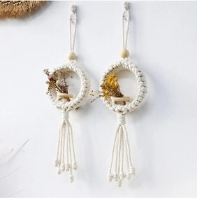 Close-up of Macrame wall hanging with wooden beads and dried flower bouquets on white wall