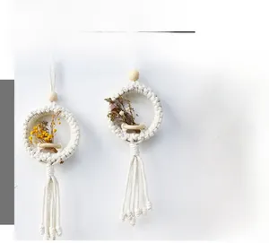 Detail of bohemian hand-woven wall hanging with cotton rope, wooden beads and dried flowers