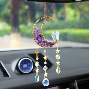 Detail view of crescent moon suncatcher with amethyst stones and crystals in car interior