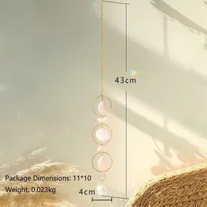 Pink quartz moon phase suncatcher with crystal ball hanging in natural sunlight shadow