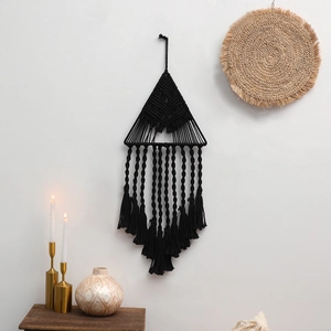 Dettaglio di un arazzo macramè nero con design a triangolo e decorazioni in frange di cotone