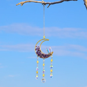 Detail of moon suncatcher with amethyst stones and crystal ball hanging from a branch