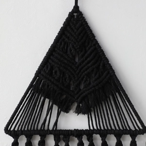 Dettaglio dell'arazzo bohémien nero fatto a mano con trame geometriche e lunghe frange