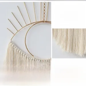 Detail of handmade macrame wall hanging with golden evil eye metal frame and fringe