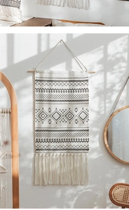 Detail of bohemian hand-woven tapestry featuring black geometric lines and cotton tassels