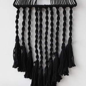 Dettaglio di decorazione murale boho intrecciata a mano nera con nappe e frange eleganti