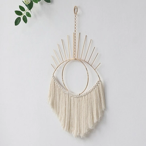 Detail of bohemian eye wall hanging with gold metal frame and cotton fringe tassels