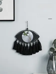 Détail d'un miroir mural bohème œil de protection avec des glands noirs décoratifs