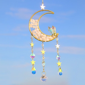 Golden moon suncatcher with pink crystal stones and star pendants against a blue sky