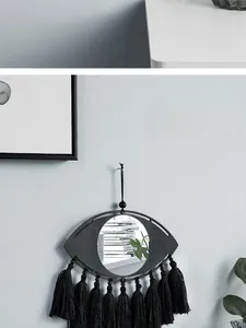 Détail d'un miroir mural bohème avec cadre en bois noir et pompons en coton épais
