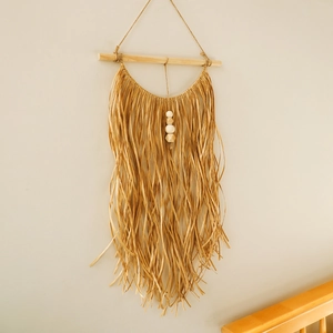 Bohemian handmade raffia wall hanging with wooden beads on a light wooden stick